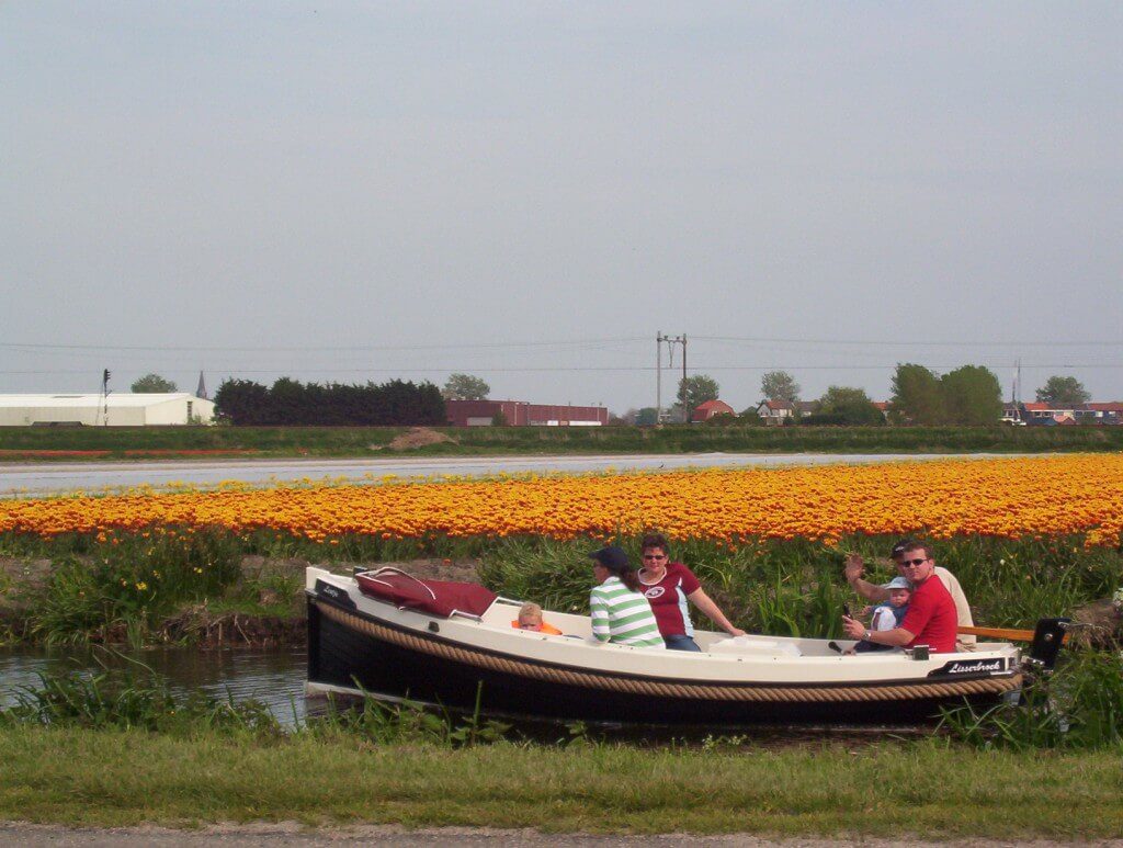 An image of a small boat on a canal beside a field of tulips near Lisse, in the Netherlands. Photography by Frame To Frame - Bob and Jean.