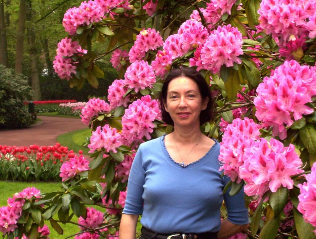 An image of Jean standing beside a Rhododendron bush at Keukenhof Gardens near Lisse, in the Netherlands. Photography by Frame To Frame - Bob and Jean. 