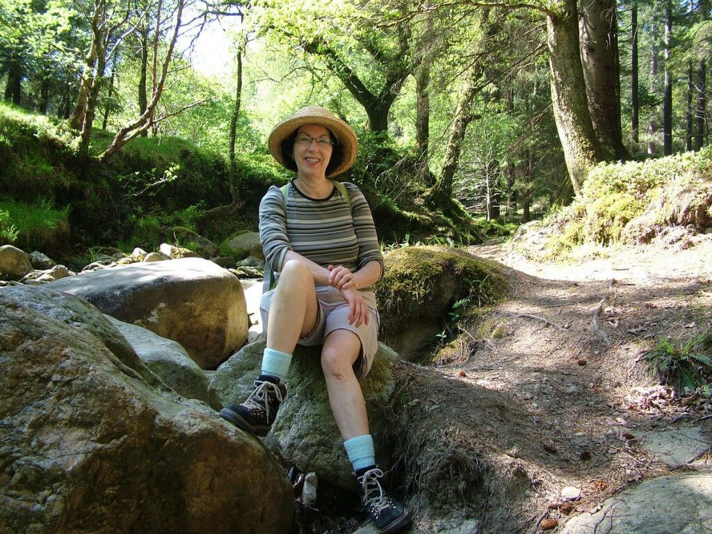 An image of Jean sitting near the Poulanass Waterfall in Wicklow Mountains National Park, County Wicklow, Ireland. Photography by Frame To Frame - Bob and Jean.