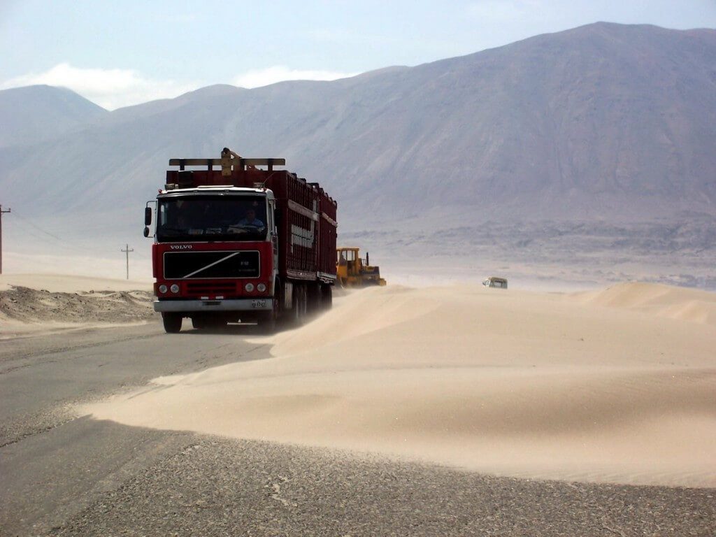 truck drives around sanddunes on pan american highway in peru - frame to frame