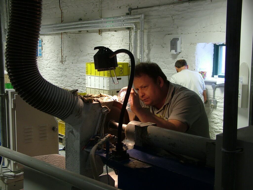 An image of a glass cutter, cutting a crystal goblet at the Waterford Crystal factory in Waterford, Ireland. Photography by Frame To Frame - Bob and Jean.