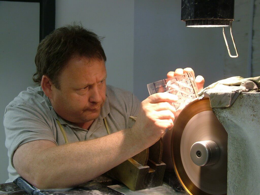 An image of a glass cutter, cutting a crystal goblet at the Waterford Crystal factory in Waterford, Ireland. Photography by Frame To Frame - Bob and Jean.