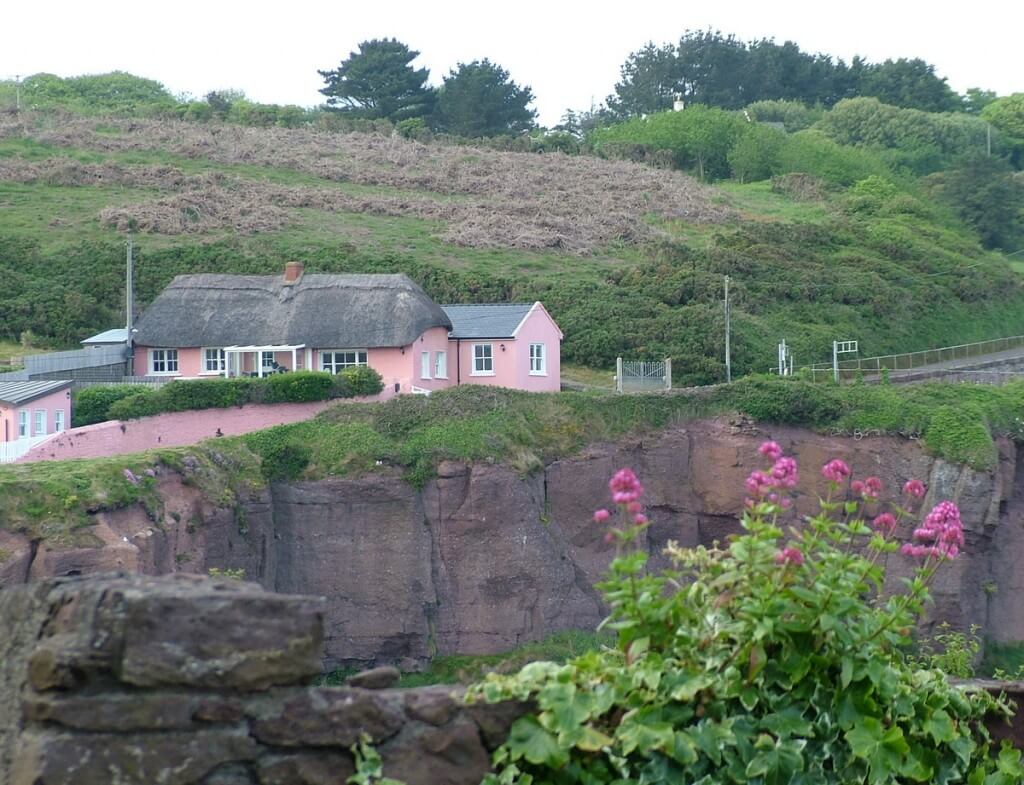 an image of a pink thatched cottage in dunmore east in county waterford - ireland