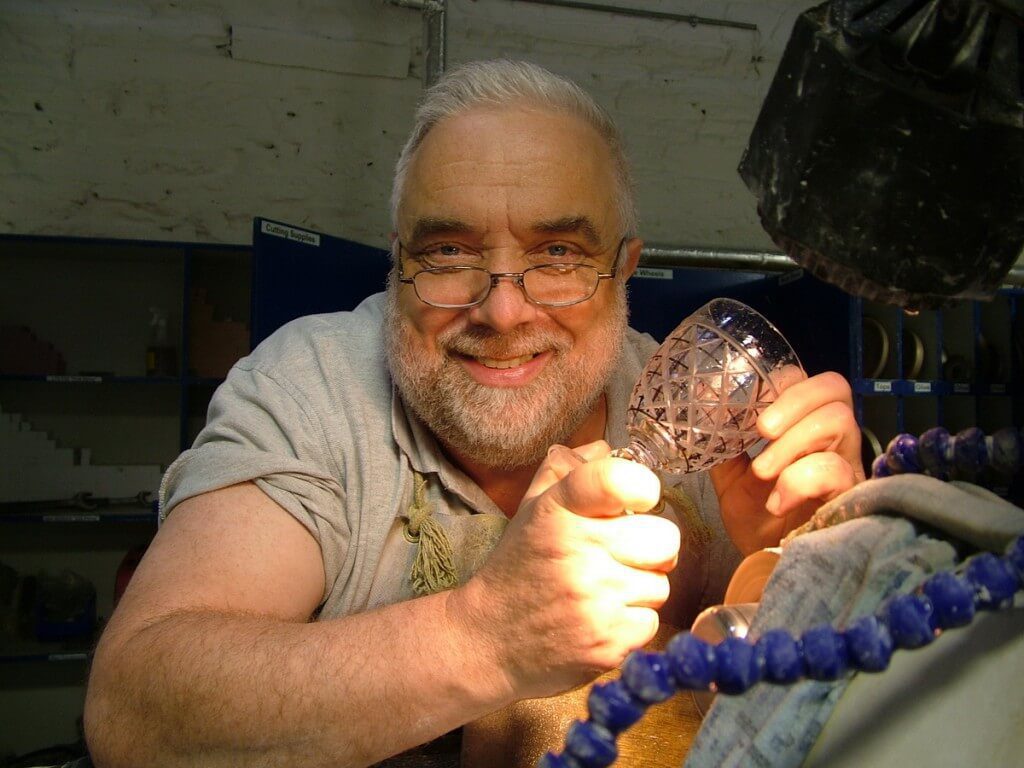 An image of a glass cutter taking a happy break from cutting a goblet at the Waterford Crystal factory in Waterford, Ireland. Photography by Frame To Frame - Bob and Jean.