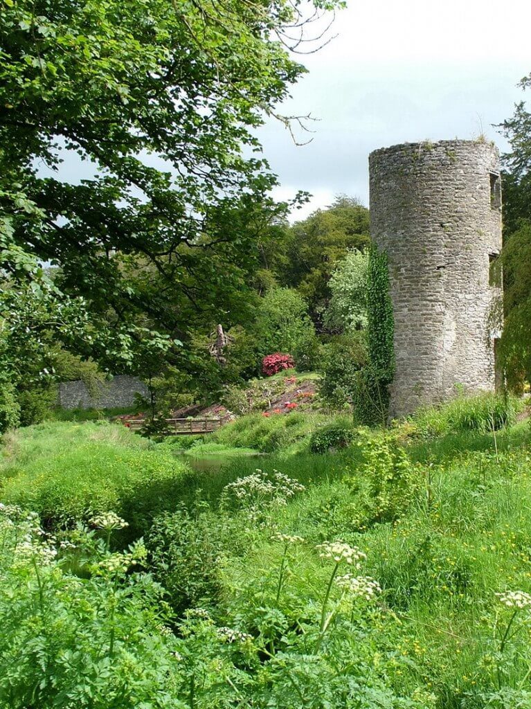 An image of a stone tower beside gardens and a stream at Blarney Castle in County Cork, Ireland. Photography by Frame To Frame - Bob and Jean.