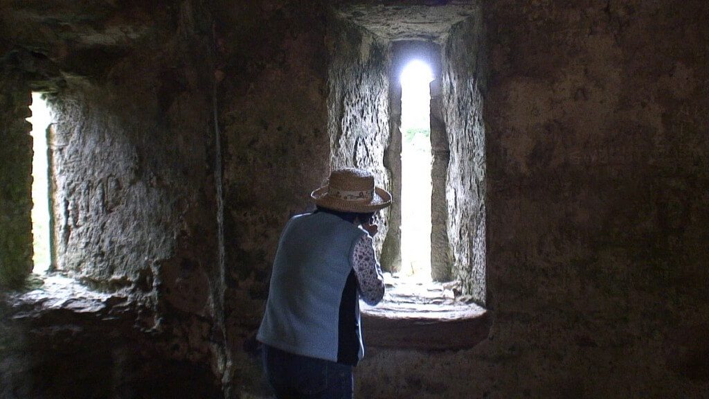 An image of Jean taking a picture through a window in the wall of Blarney Castle near Cork in Ireland. Photography by Frame To Frame - Bob and Jean.