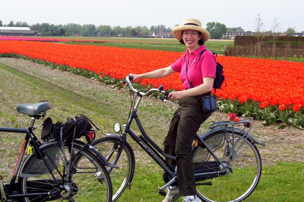 An image of Jean on a rental bicycle beside a tulip field near Lisse in the Netherlands. Photography by Frame To Frame - Bob and Jean.
