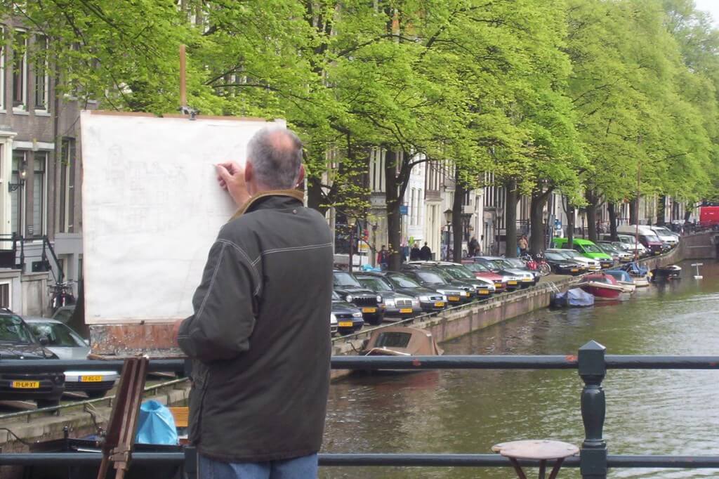 artist paints on canal in amsterdam