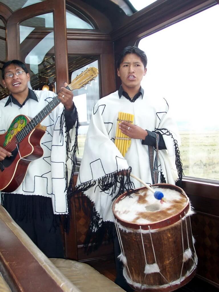 Musician plays a Bamboo Zampona Pan on board the PeruRail Andean Explorer train in Peru, South America