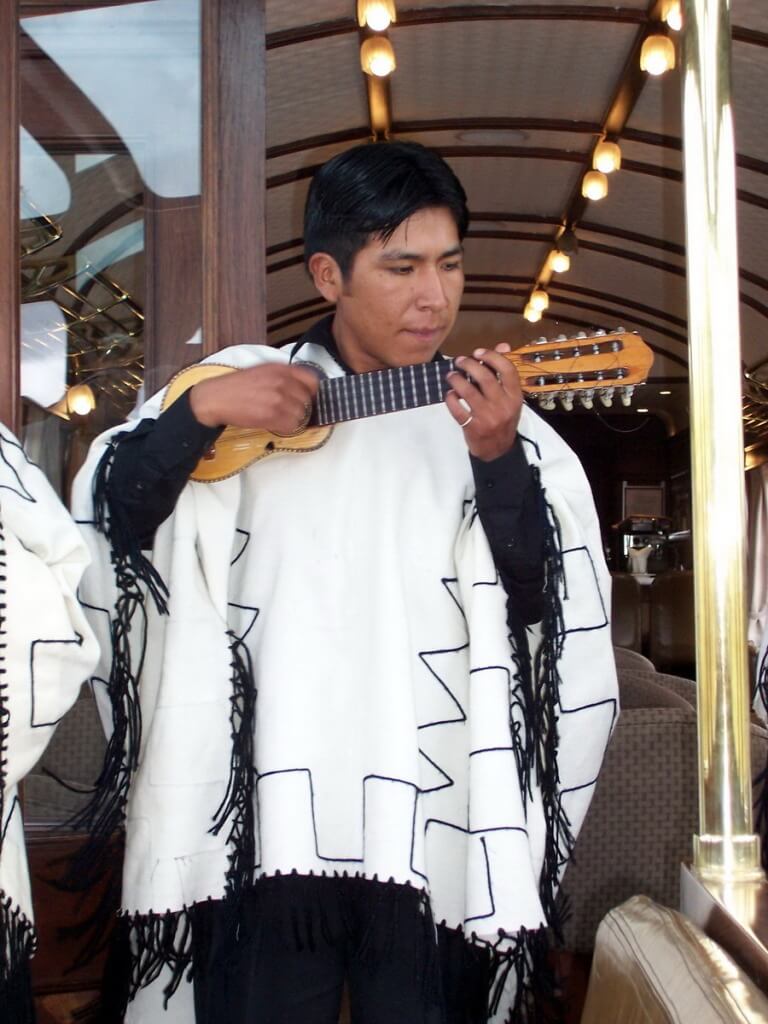 Musician plays a charango guitar on board the PeruRail Andean Explorer train in Peru, South America