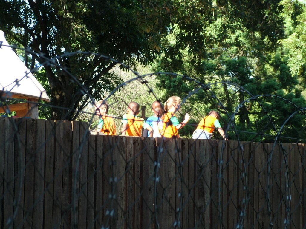 Children playing behind school fence and razor wire in Sabie, South Africa