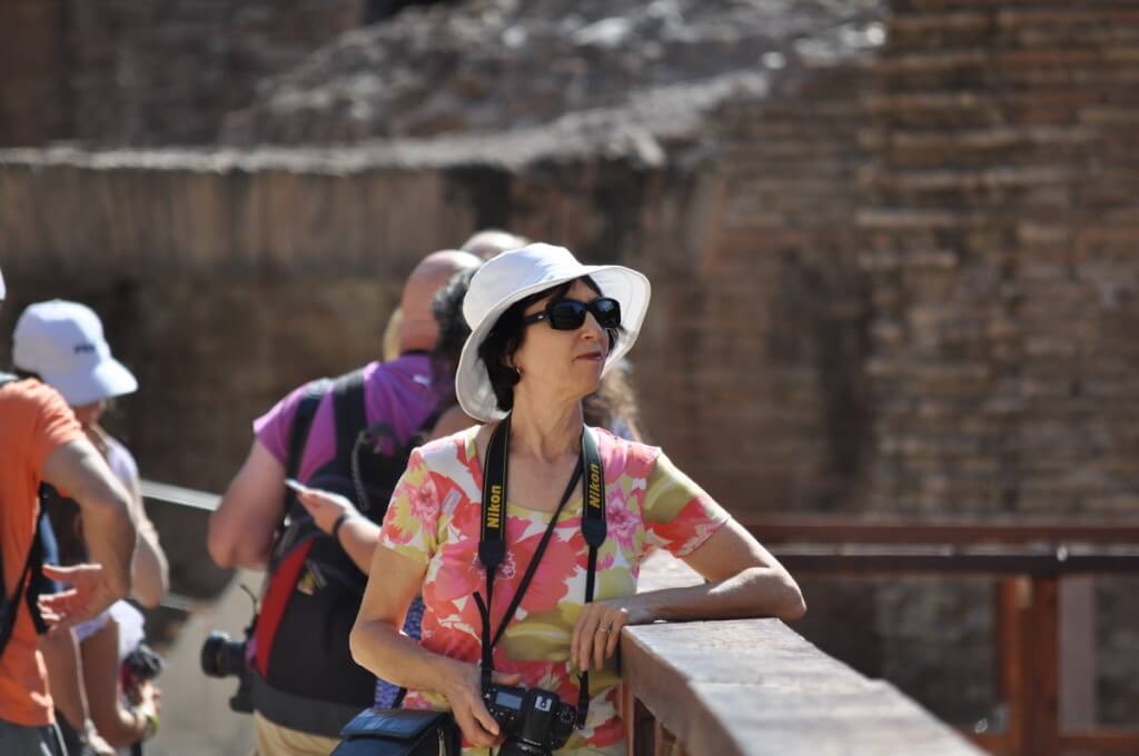 An image of Jean standing on the restored wooden floor of the Roman Colosseum in Rome, Italy. Photography by Frame To Frame - Bob and Jean.
