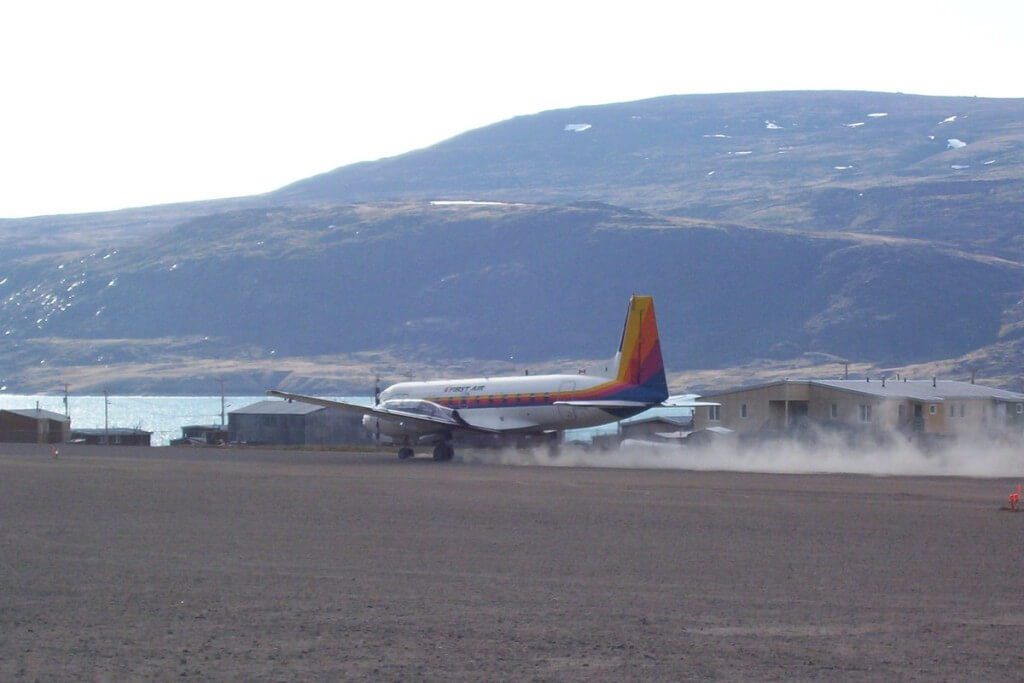 photograph of a First Air prop plane landing on the dirt runway in Pangnirtung on Baffin Island in Nunavut, Canada