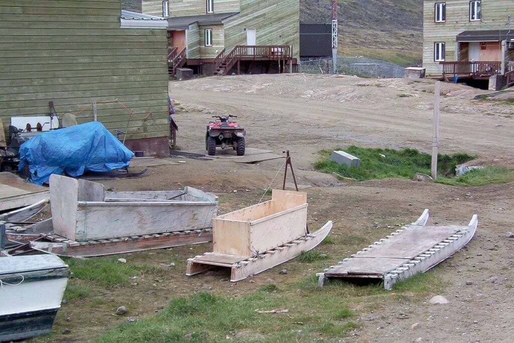 photograph of inuit toboggans sitting on green grass in Pangnirtung, Nunavut, Canada.