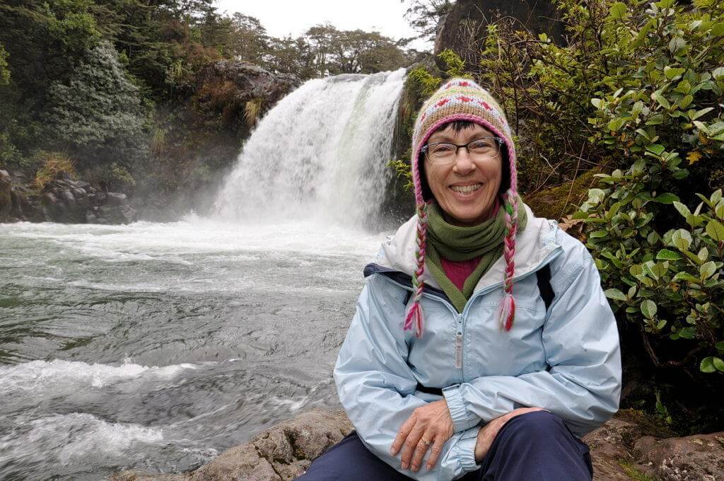 An image of Jean sitting on the rocks at Tawhai Falls in Tongariro National Park in New Zealand, where Gollum in Lord of Rings sat on the edge of Gollum's Pool. Photography by Frame To Frame - Bob and Jean.