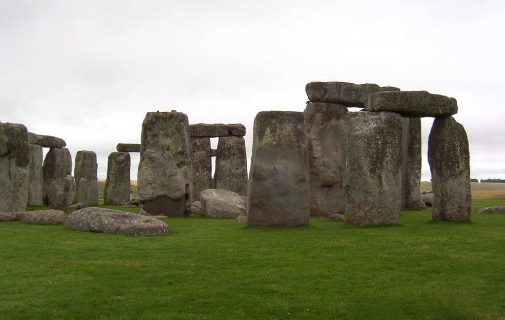An image of several stone pillars holding up lintel stones at Stonehenge in Wiltshire at dusk in England. Photography by Frame To Frame - Bob and Jean
