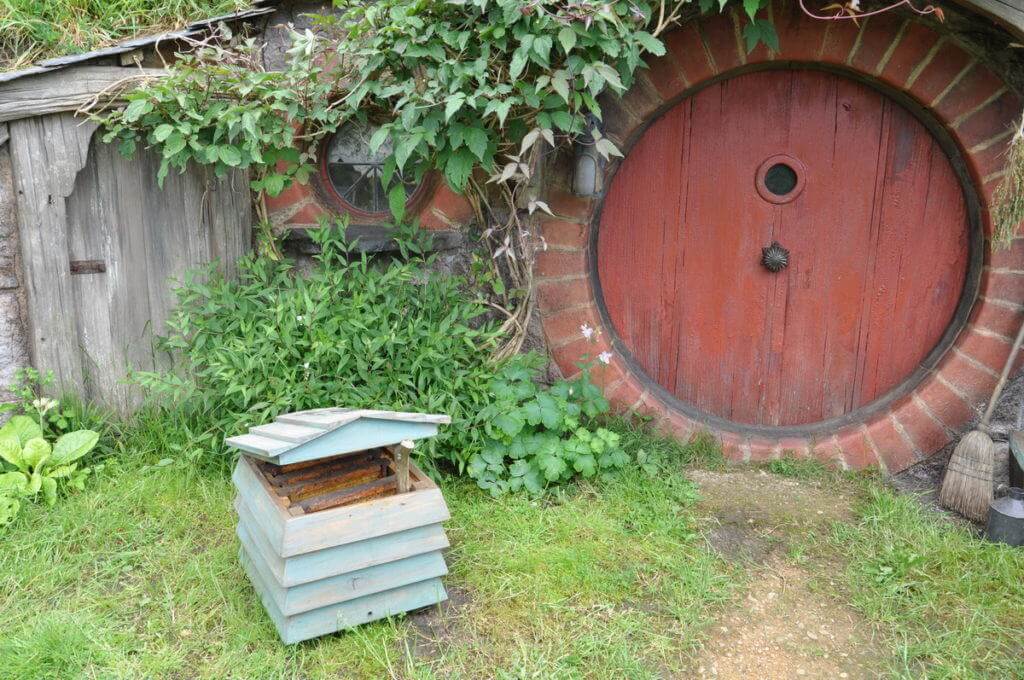 An image of an open beehive in front of the Beekeepers hobbit hole at Hobbiton in New Zealand. Photography by Frame To Frame - Bob and Jean.