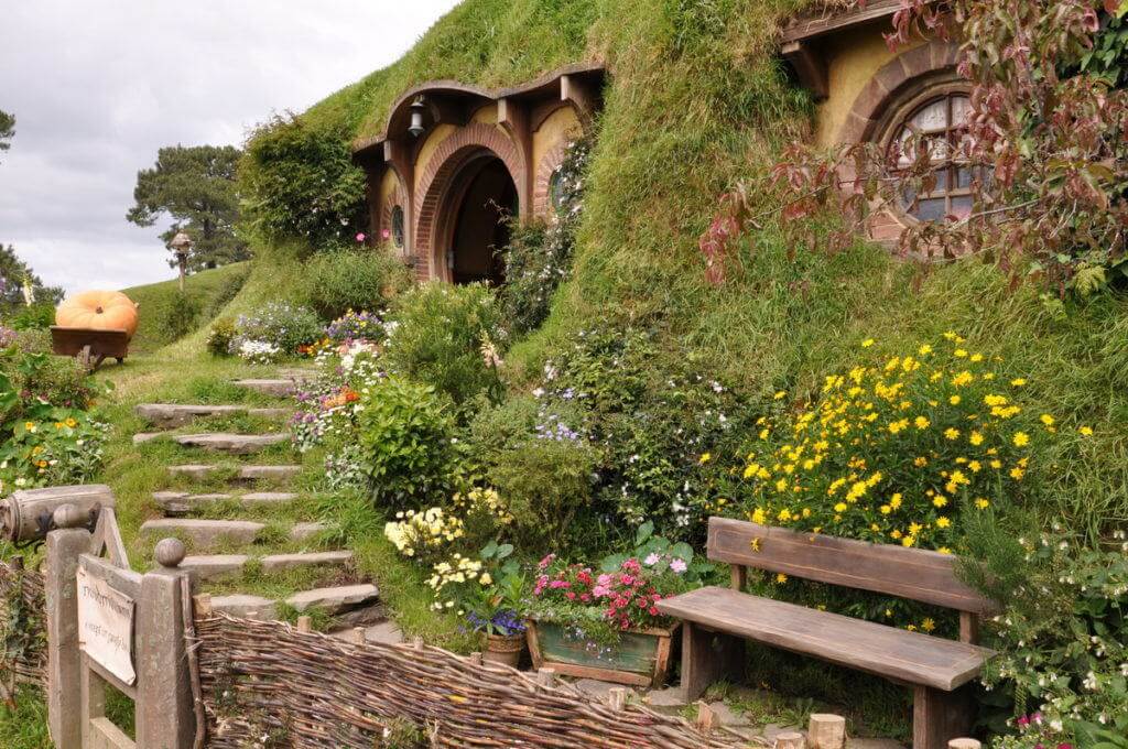 An image of the flower garden and stone steps our front of Bilboo Baggins Home at Hobbiton in New Zealand. Photography by Frame To Frame - Bob and Jean.