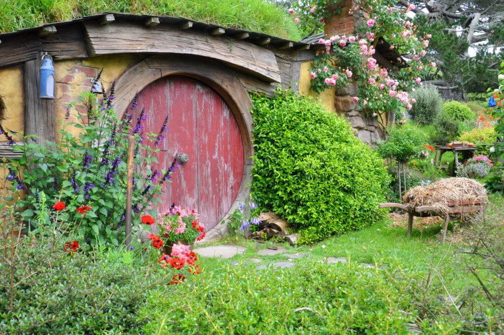 An image of a hobbit hole with a red door at Hobbiton, in New Zealand. Photography by Frame To Frame - Bob and Jean.