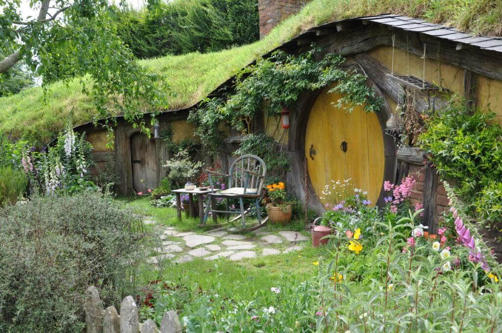 An image of a hobbit hole with a yellow door at Hobbiton in New Zealand. Photography by Frame To Frame - Bob and Jean.