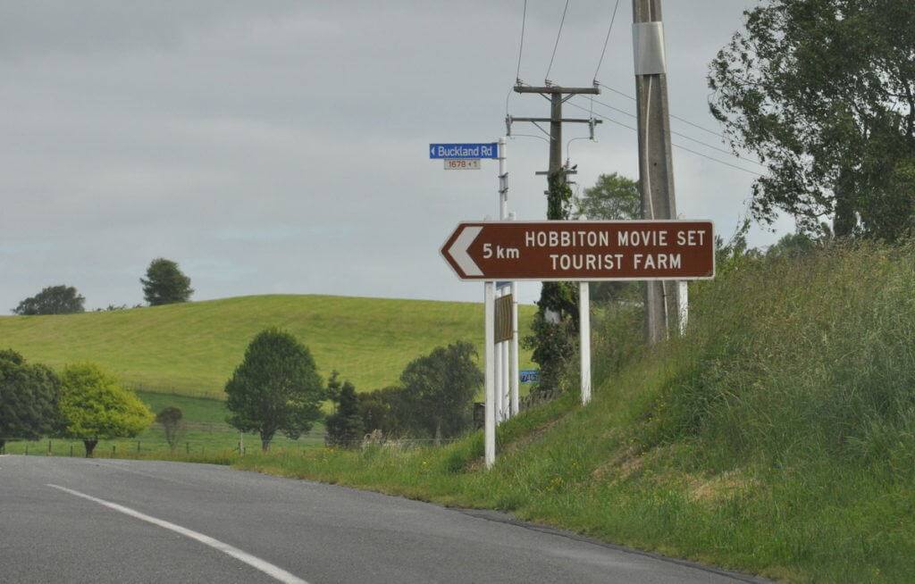An image of the 5 km highway sign giving directions to the Hobbiton Movie Set Tourist Farm in New Zealand. Photography by Frame To Frame - Bob and Jean.