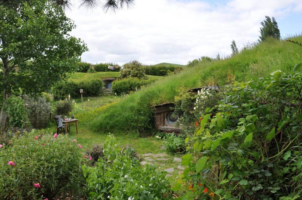 An image of various hobbit holes among green hills at Hobbiton in New Zealand. Photography by Frame To Frame - Bob and Jean.
