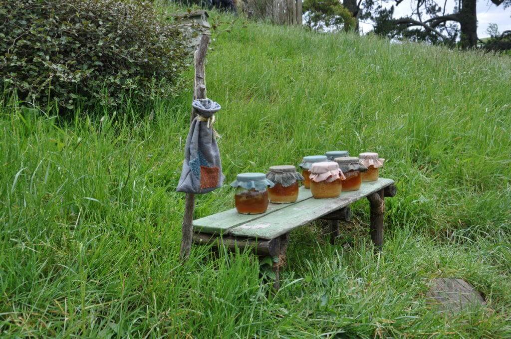 An image of seven jars of honey sitting on a wooden table at the home of shire beekeeper at Hobbiton in New Zealand. Photography by Frame To Frame - Bob and Jean.