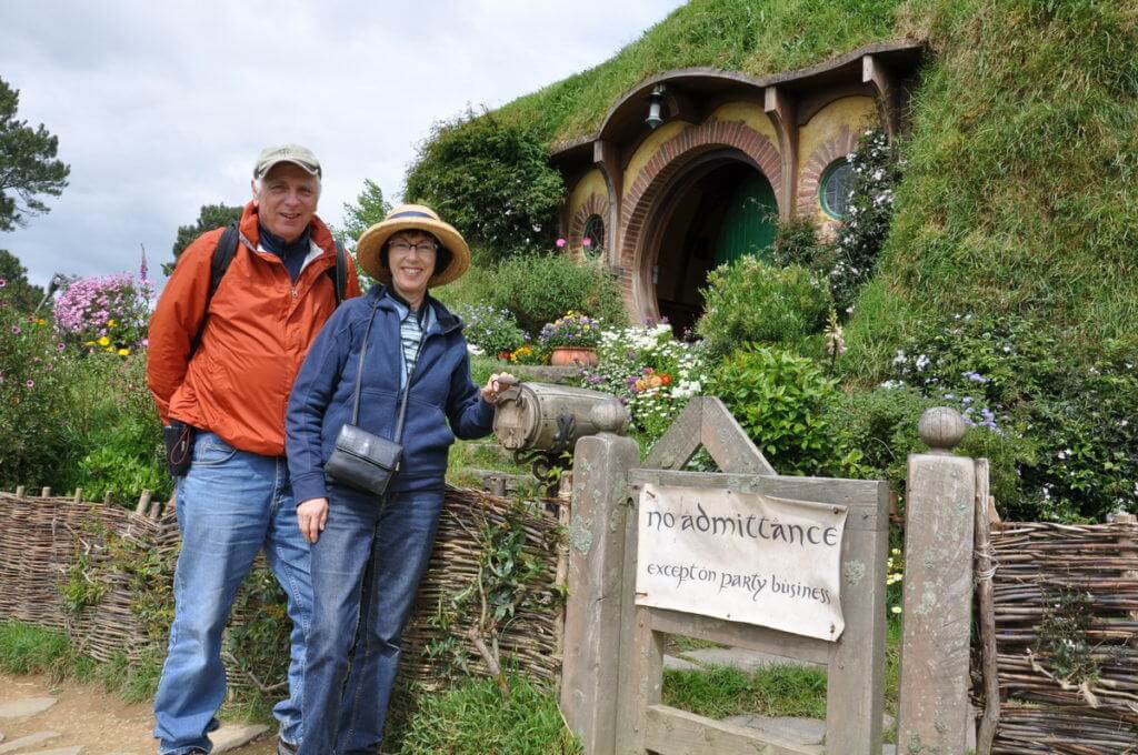 An image of Bob and Jean standing outside of Bilbo Baggins House at Hobbiton in New Zealand. Photography by Frame To Frame - Bob and Jean.