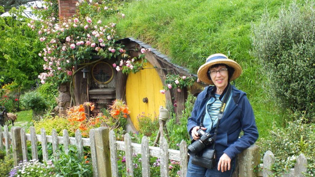 An image of Jean standing in front of Sams House at Hobbiton in New Zealand. Photography by Frame To Frame - Bob and Jean.