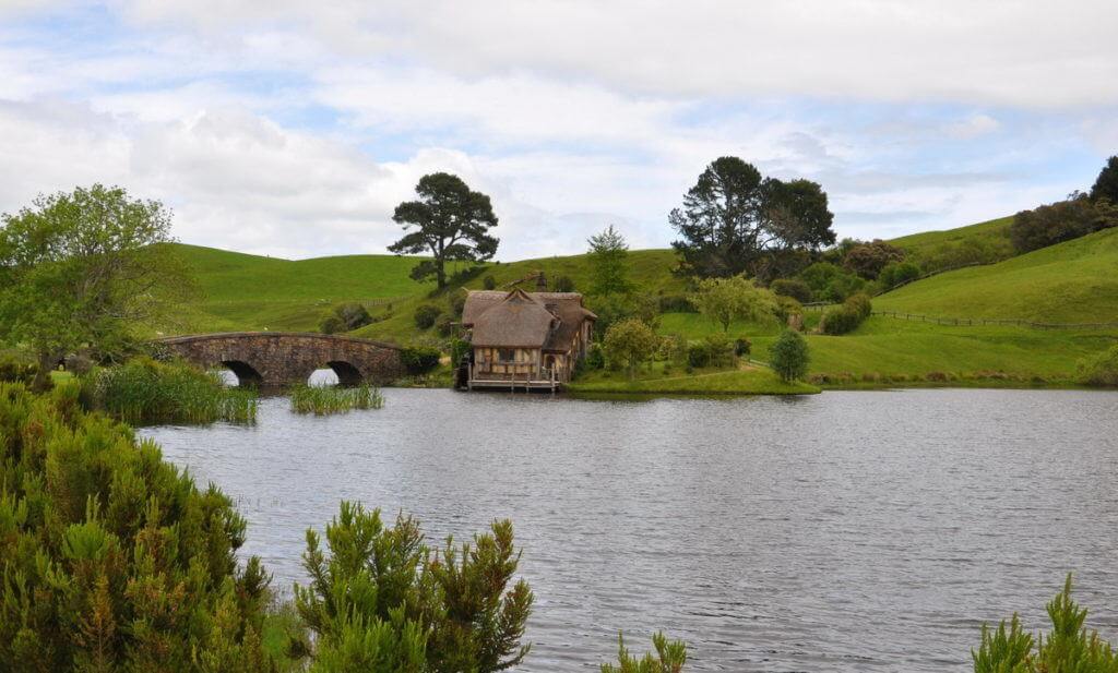 An image of the old water mill beside the stone bridge over the pond at Hobbiton in New Zealand. Photography by Frame To Frame - Bob and Jean.