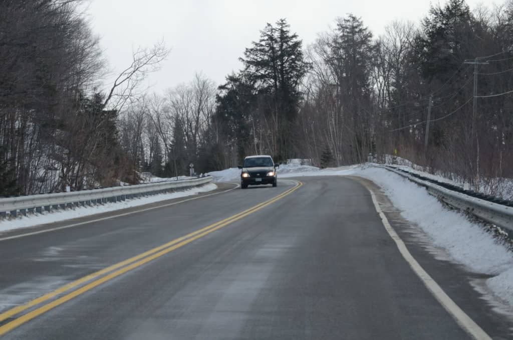 Image of a car driving on hwy 60 in the winter in Algonquin Park in Ontario, Canada. Photography by Frame To Frame - Bob and Jean