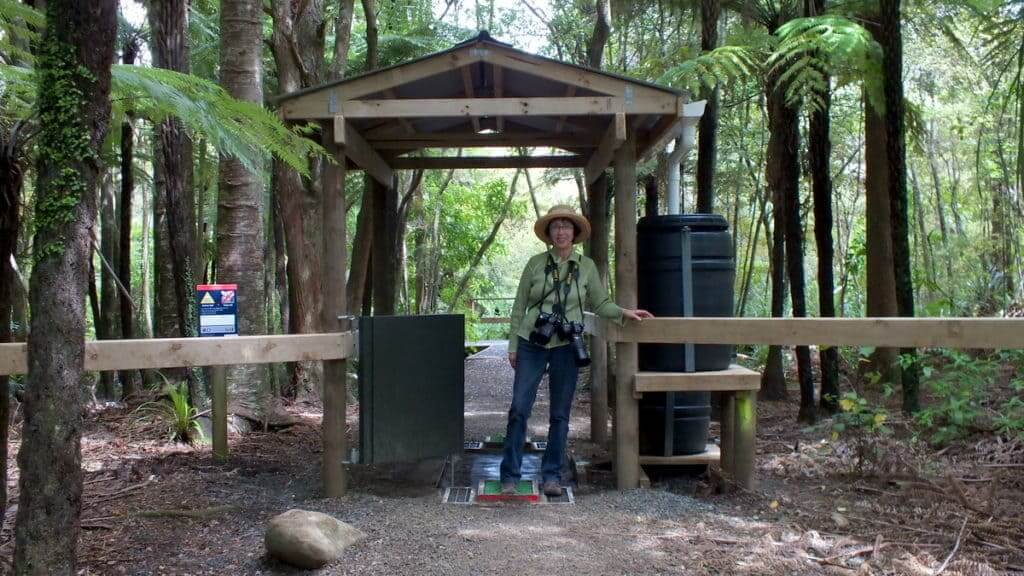 An image of Jean at the entrance gate to the Waitakere Ranges hiking trails, New Zealand.