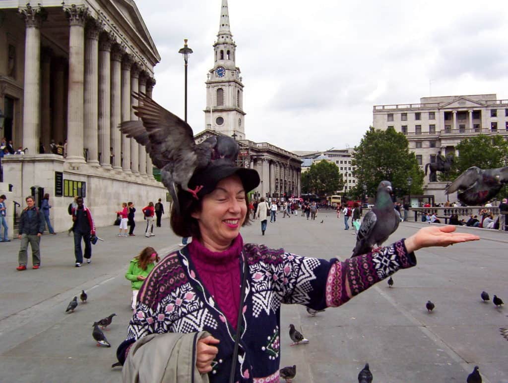 An image of pigeons sitting on a person in Trafalgar Square in London, England.