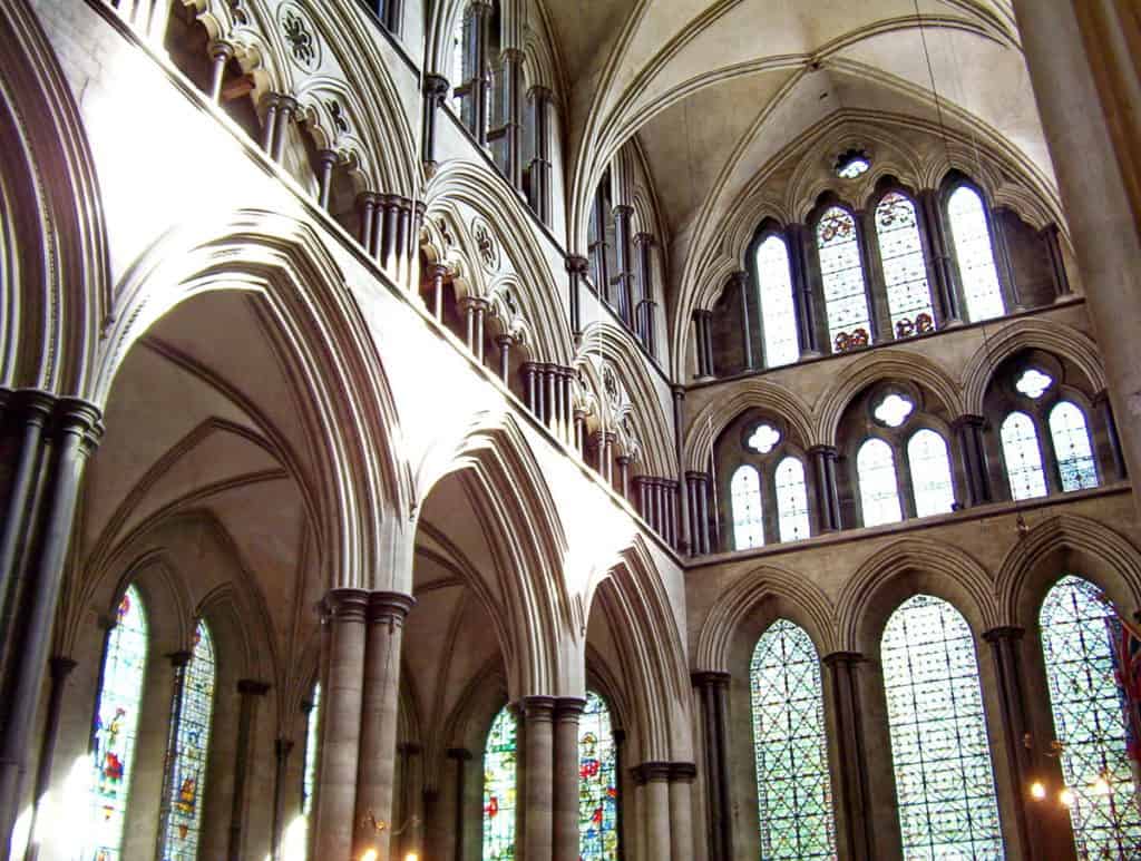 the interior of Salisbury Cathedral showing pointed arches, columns, windows and doors.