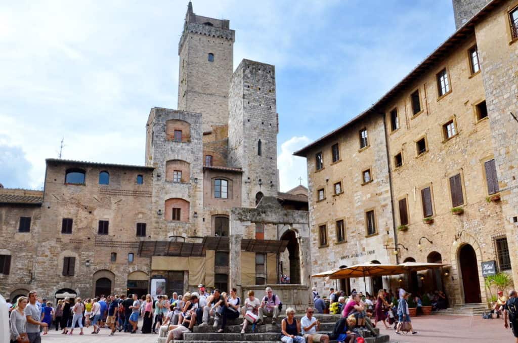 Image of tourists around the well and in Piazza della Cisterna, in San Gimignana, Italy. 