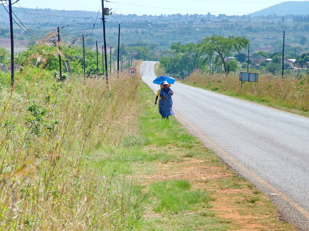 a lady walking along a paved road in swaziland, africa