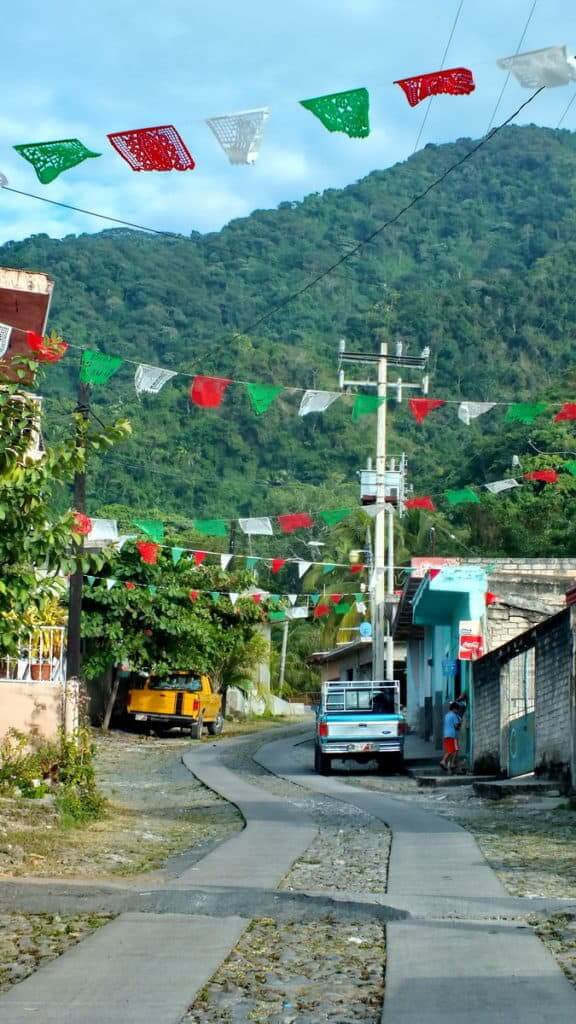 Image of red, white and green banners gaily strewn overhead in the town of La Bajada, Mexico.