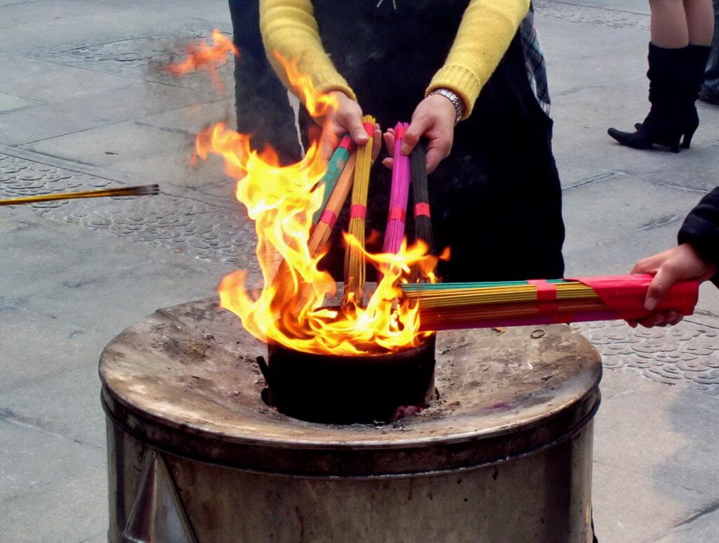 People light their incense sticks over a flame inside the City God Temple of Shanghai, in Shanghai, China.