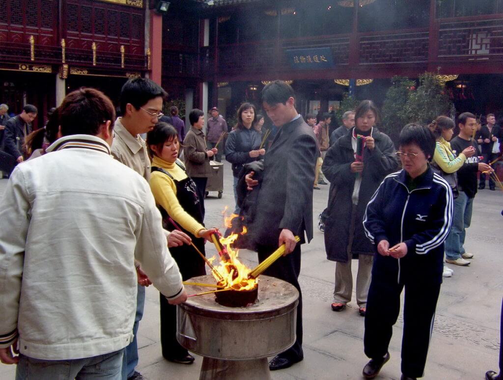 People lite their incense sticks in the main courtyard of the City God Temple of Shanghai in China.