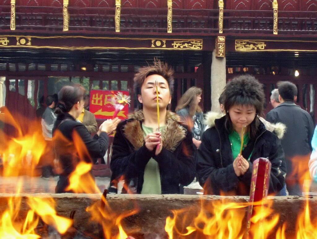 A young couple pray will holding their burning incense sticks inside the City God Temple of Shanghai, in Shanghai, China.