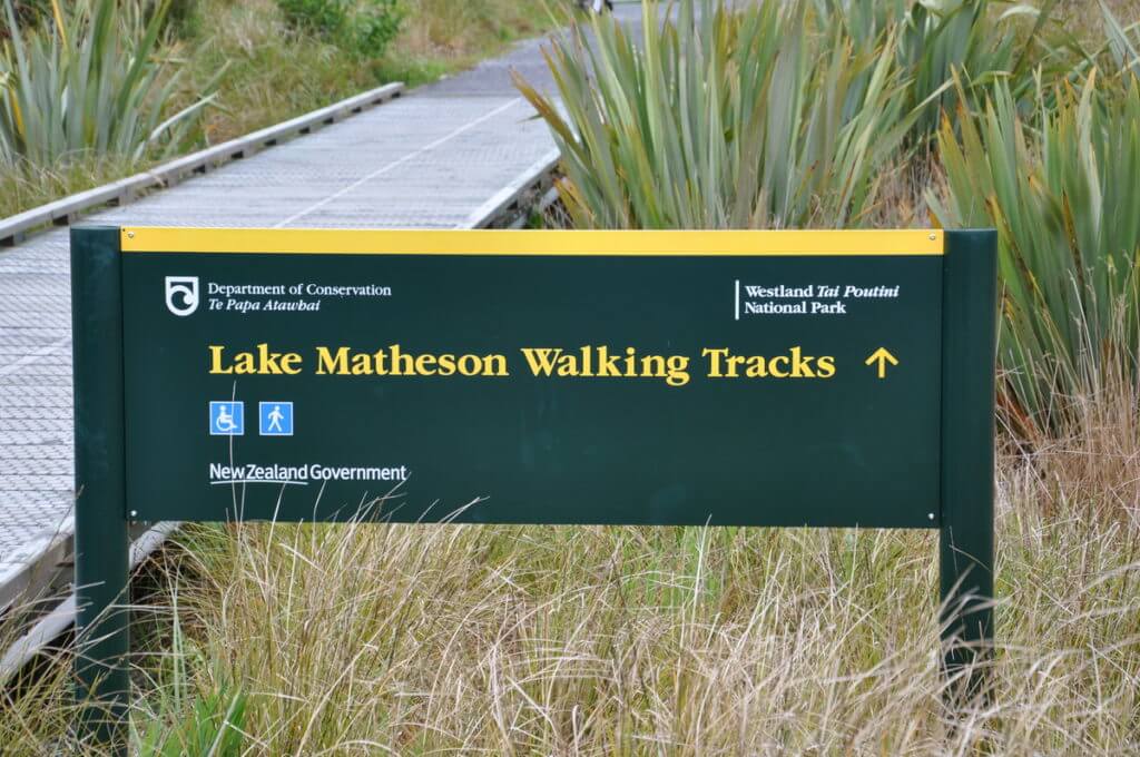 a sign for lake matheson walking tracks, south island, new zealand