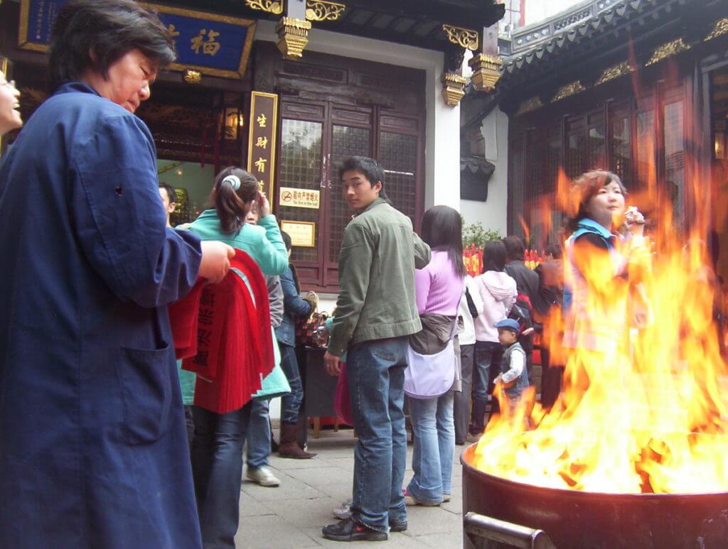 People lineup to receive their red joss paper outside the City God Temple of Shanghai in China.