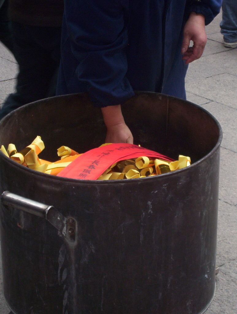 A container of red joss papers are carried to the burning pit inside the City God Temple of Shanghai in China.