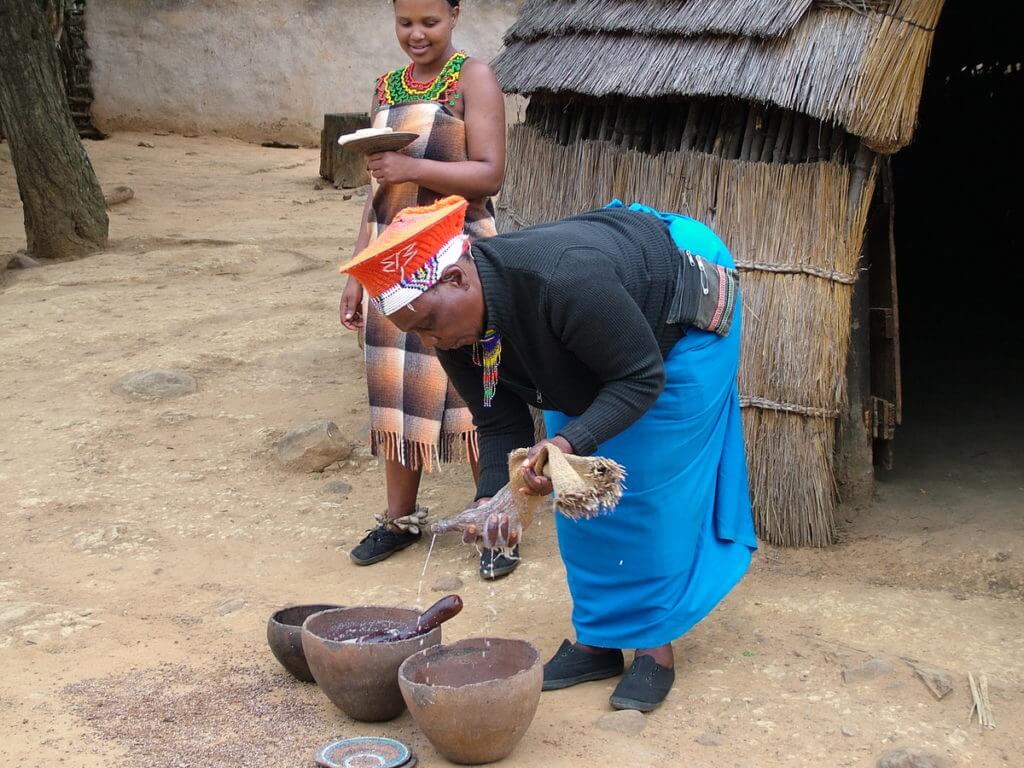 a zulu woman straining beer, shakaland, kwazulu-natal, south africa