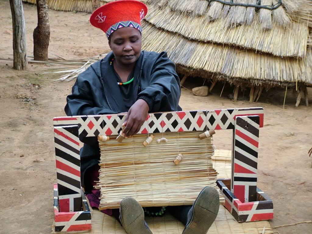 a married zulu woman weaving a grass mat, shakaland, kwazulu-natal, south africa