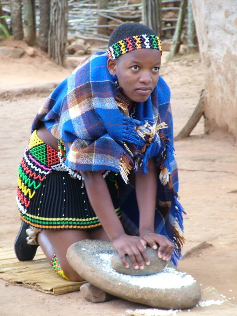 a zulu maiden grinding grain, shakaland, kwazulu-natal, south africa