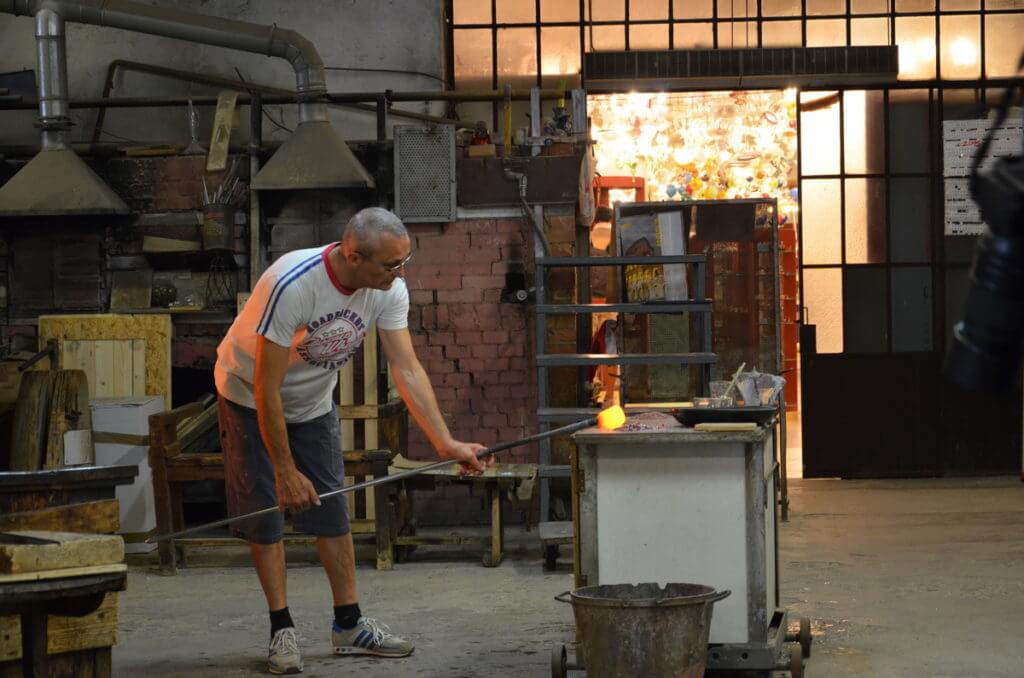 an artisan with a blow pipe and marver, gino mazzuccato glass factory, murano island, venice, italy