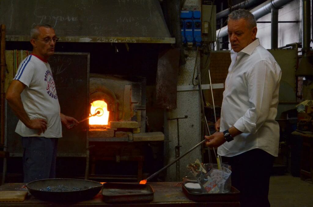an artisan inserting a bubble into the glory hole, gino mazzuccato glass factory, murano island, venice, italy