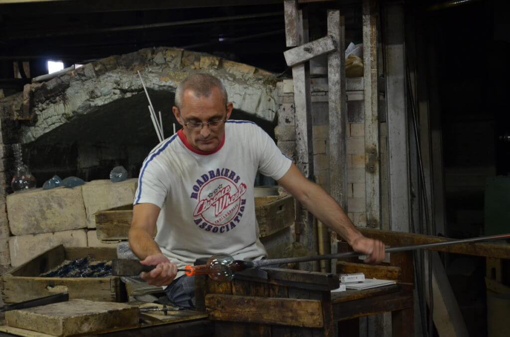 an artisan using large tweezers to shape glass, gino mazzuccato glass factory, murano island, venice, italy