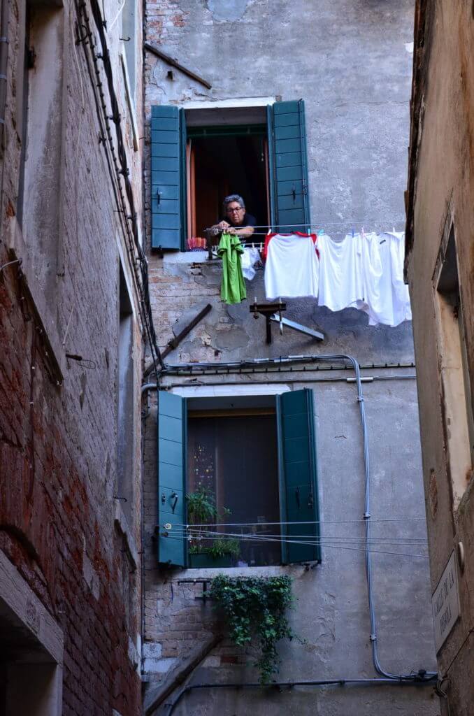 a venetian hanging out laundry, venice, italy